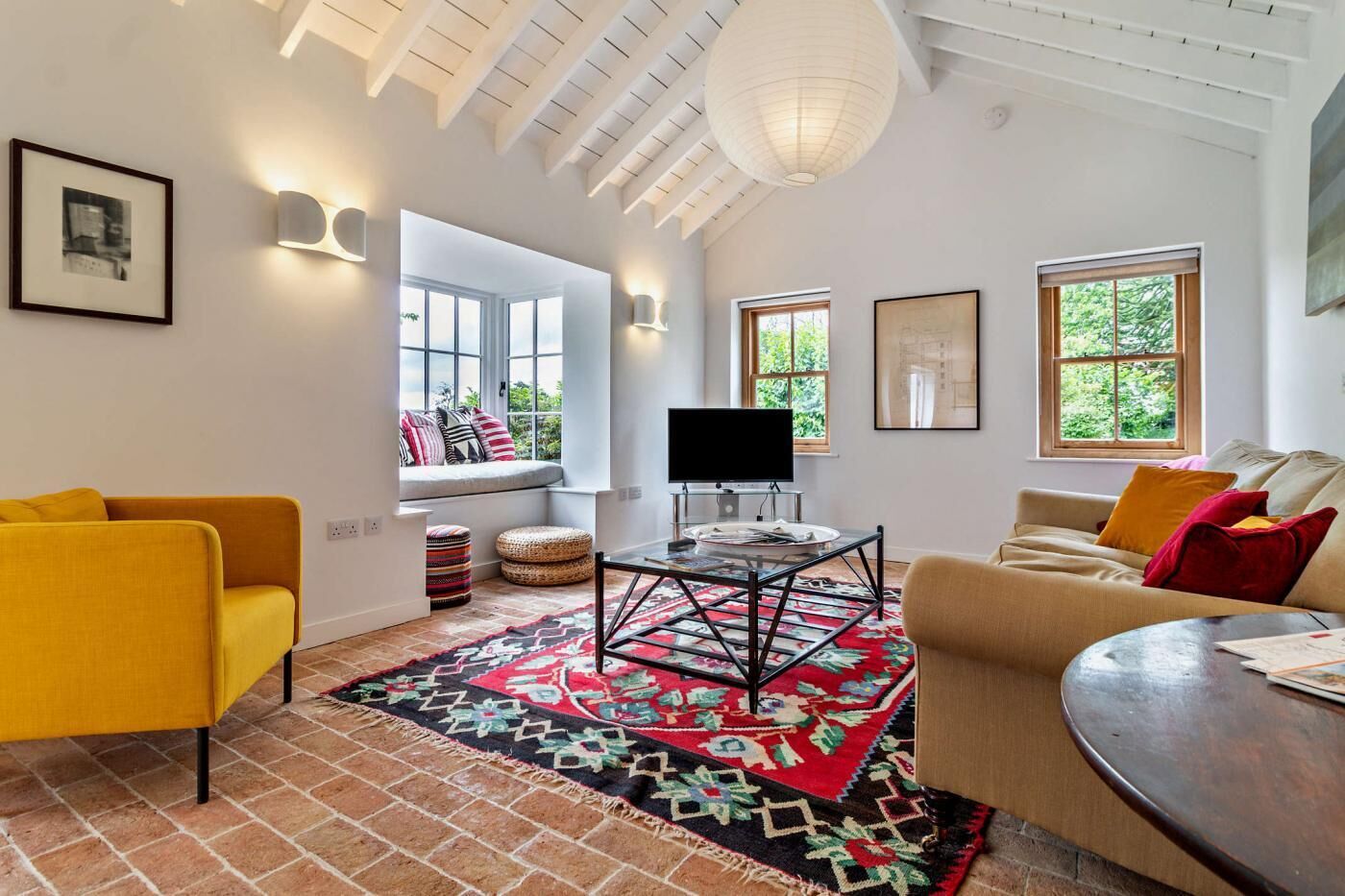 A modern living room with a sofa, a television, and a patterned rug.