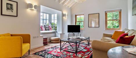 A modern living room with a sofa, a television, and a patterned rug.