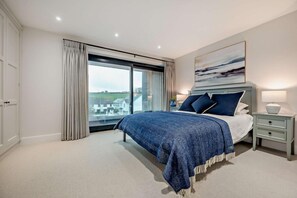 A bedroom with a large bed, a nightstand, a lamp, and a painting on the wall. - 2 Bed in Harlyn Bay (oc-s28921) (Harlyn Bay)