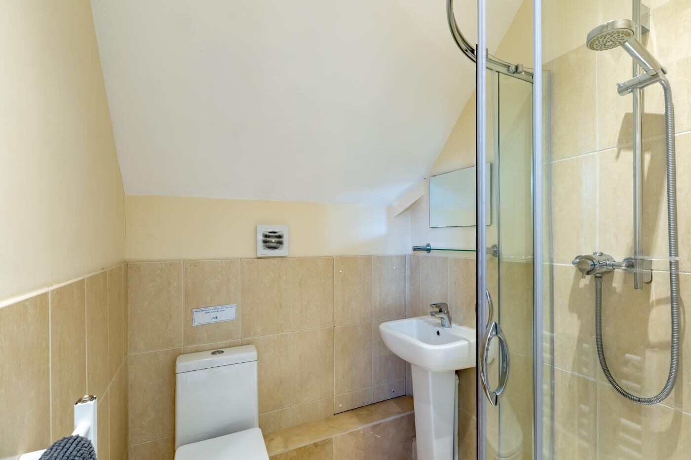 A modern bathroom with a glass shower enclosure, a pedestal sink, and a toilet.