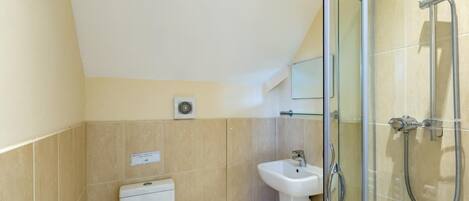 A modern bathroom with a glass shower enclosure, a pedestal sink, and a toilet.