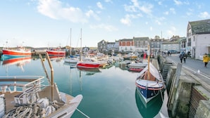 Un porto con barche ormeggiate, una passeggiata lungo l'acqua e edifici sullo sfondo.