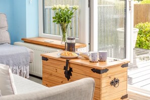 Une commode en bois, une cafetière, une assiette de nourriture et deux tasses sur une table en bois.