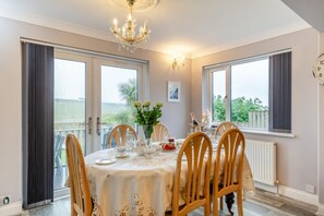 A dining room with a table set for six, a chandelier, and a view of the outdoors. - 3 Bed in Hope Cove (oc-hocov) (Hope Cove)