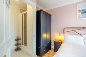 A bedroom with a bed, bedside table, lamp, wardrobe, and a door leading to a bathroom. - 3 Bed in Hope Cove (oc-hocov) (Hope Cove)