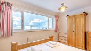 Un dormitorio con una cama grande, un armario de madera, un radiador y una ventana con cortinas.