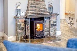 A stone fireplace with a wood-burning stove, two lanterns, and a thermostat. - 3 Bed in Hope Cove (oc-hocov) (Hope Cove)