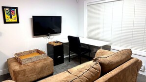 A living room with a flat-screen TV, a desk, a chair, and two sofas. - Charming 2 BR 1BA Basement suit in White Rock with WiFi (White Rock)