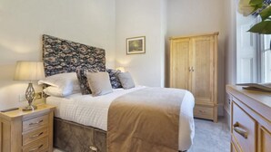 Quarto com uma cama, mesas de cabeceira, um guarda-roupa e um quadro na parede.