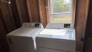 Zwei weiße Whirlpool Waschmaschinen mit Frontlader in einem Zimmer mit Holzboden und Fenster.