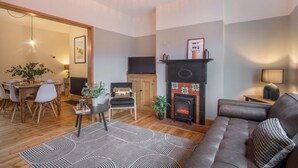 Un salon chaleureux avec une cheminée, un coin repas et un canapé.