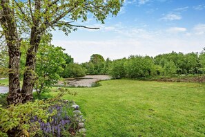 A grassy field with a pond, trees, and a stone wall. - 4 Bed in Rhayader (oc-m28919) (Nantmel)