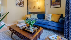 A modern living room with a blue sofa, a coffee table with a tray, and framed artwork on the walls. - 3 Bed in Canterbury (oc-86139) (Canterbury)