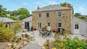 Una casa de piedra con patio, mobiliario exterior y jardín.