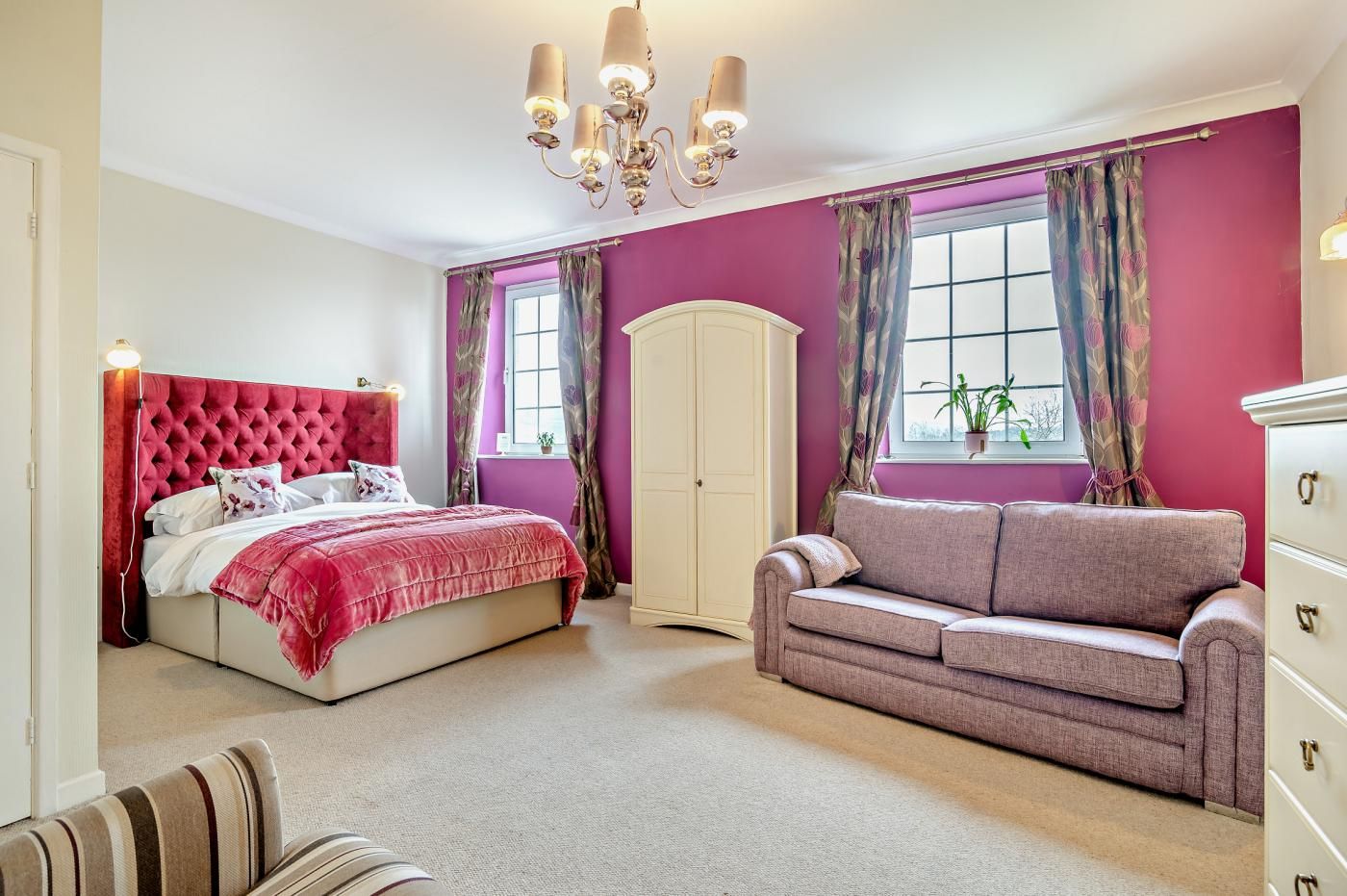 Une chambre à coucher avec un grand lit, un canapé, une armoire et un lustre.