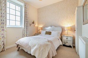 A bedroom with a bed, two bedside tables, a radiator, and a window with curtains. - 9 Bed in The Dardy (oc-t28942) (Crickhowell)
