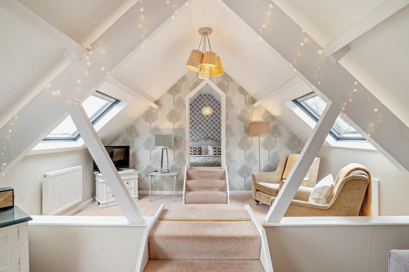 A loft bedroom with a vaulted ceiling, a bed, a desk, and a chair.