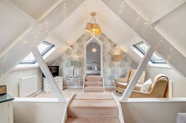 A loft bedroom with a vaulted ceiling, a bed, a desk, and a chair.