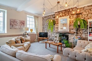 A cozy living room with a stone fireplace, a television, and comfortable seating.