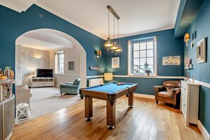 A pool table in a room with a blue wall, a television, and a seating area with a chair and a sofa. - 9 Bed in The Dardy (oc-t28942) (Crickhowell)