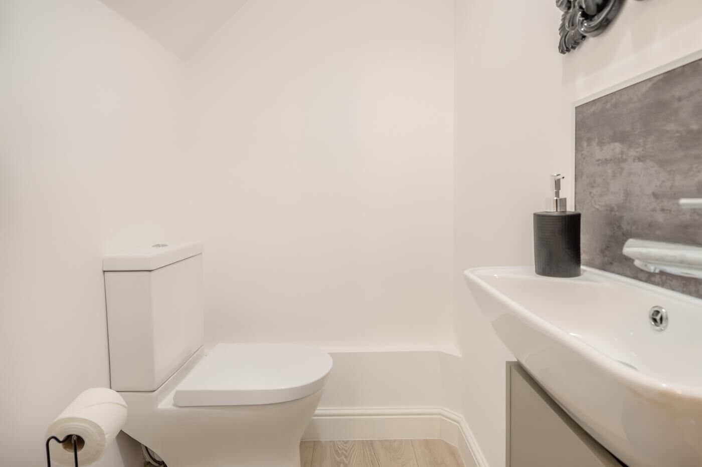 Een kleine, moderne badkamer met toilet, wastafel en toiletpapier.