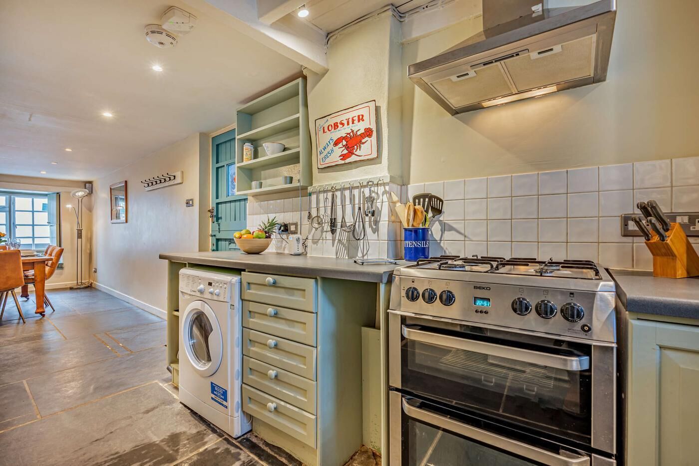 Una cocina moderna con lavadora integrada, estufa y un letrero que dice "LOBSTER ALWAYS FRESH".