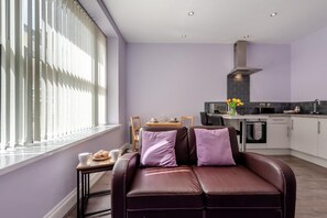 Ein modernes Wohnzimmer mit einer Couch, einem Esstisch mit Stühlen und einer Küchenzeile mit Schränken und einem Herd.