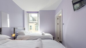 Quarto de hotel com duas camas, uma janela, televisão de tela plana e abajur.