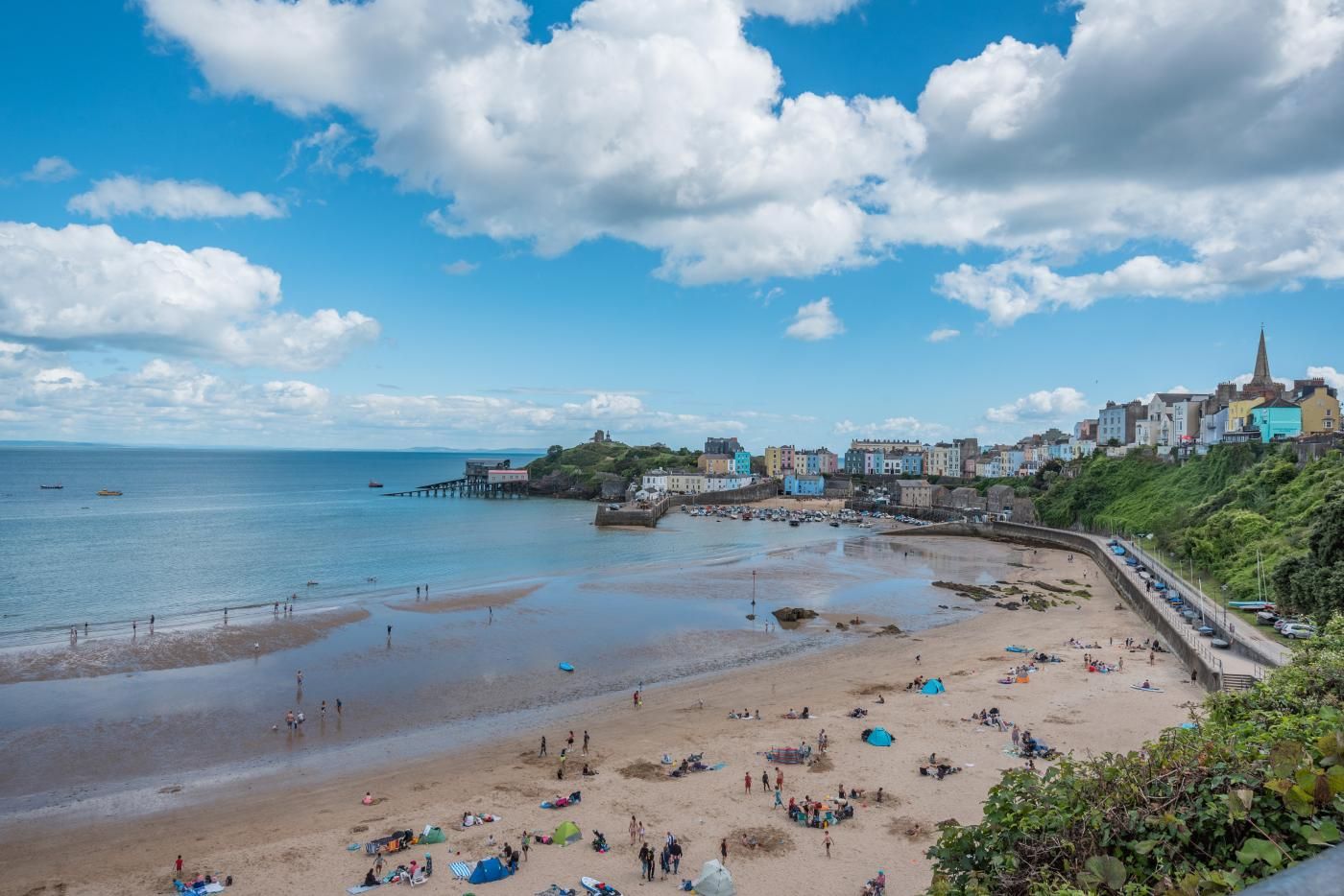 A coastal town with a sandy beach, a pier, and colorful buildings.