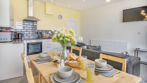 A modern kitchen with a dining area, equipped with a microwave, toaster, and oven. - 2 Bed in Tenby (oc-b28989) (Tenby)