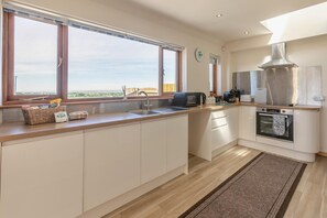 A modern kitchen with a large window, a built-in oven, and a stainless steel range hood. - 1 Bed in Four Lanes (oc-f28972) (Four Lanes)