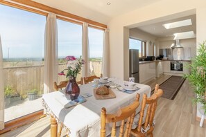 A dining area with a table set for two, a vase with flowers, and a view of the cityscape through large windows. - 1 Bed in Four Lanes (oc-f28972) (Four Lanes)