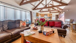 A spacious living room with leather sofas, a wooden coffee table, and a kitchen in the background. - 3 Bed in Thwing (oc-t29011) (Thwing)