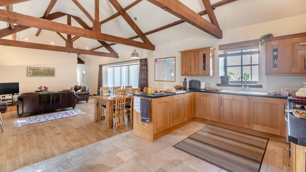A spacious kitchen with wooden beams, a dining area, and a living room with a sofa and TV. - 3 Bed in Thwing (oc-t29011) (Thwing)