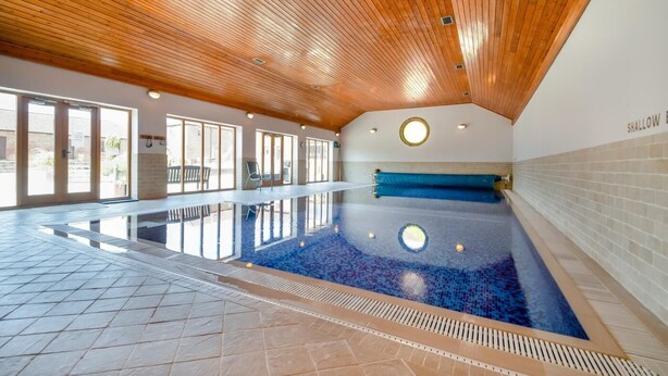 Una piscina interior con techo de madera y suelo de baldosas.