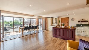 A spacious kitchen with a central island, a dining area with a table and chairs, and large sliding glass doors leading to an outdoor patio. - 4 Bed in Thwing (oc-t29013) (Thwing)