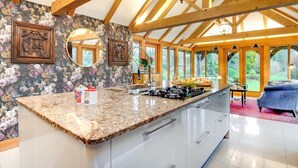 Una cocina con encimera de granito, vigas de madera y vistas al jardín.
