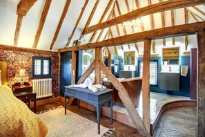 A bedroom with exposed wooden beams, a bed, a desk, and a bathroom visible through a large window. - 7 Bed in Petham (oc-r28863) (Waltham)