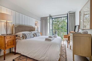 A hotel room with a large bed, bedside lamps, a wooden nightstand, a dresser, and a balcony with curtains. - 2 Bed in Padstow (oc-h29015) (Padstow)