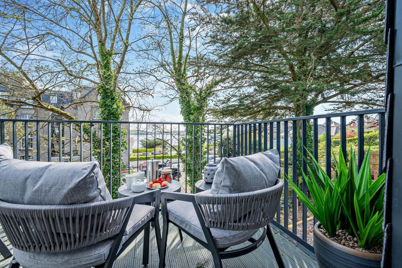 A balcony with wicker chairs, a small table, and a potted plant.