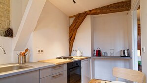 Una cocina con techo de vigas de madera, horno empotrado y un lavamanos.
