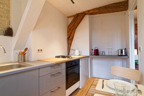 Eine Küche mit Holzbalkendecke, eingebautem Ofen und Spüle.