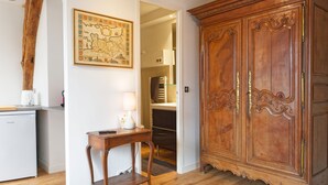 Una habitación con un armario de madera, una mesita con una lámpara y un mapa en la pared.