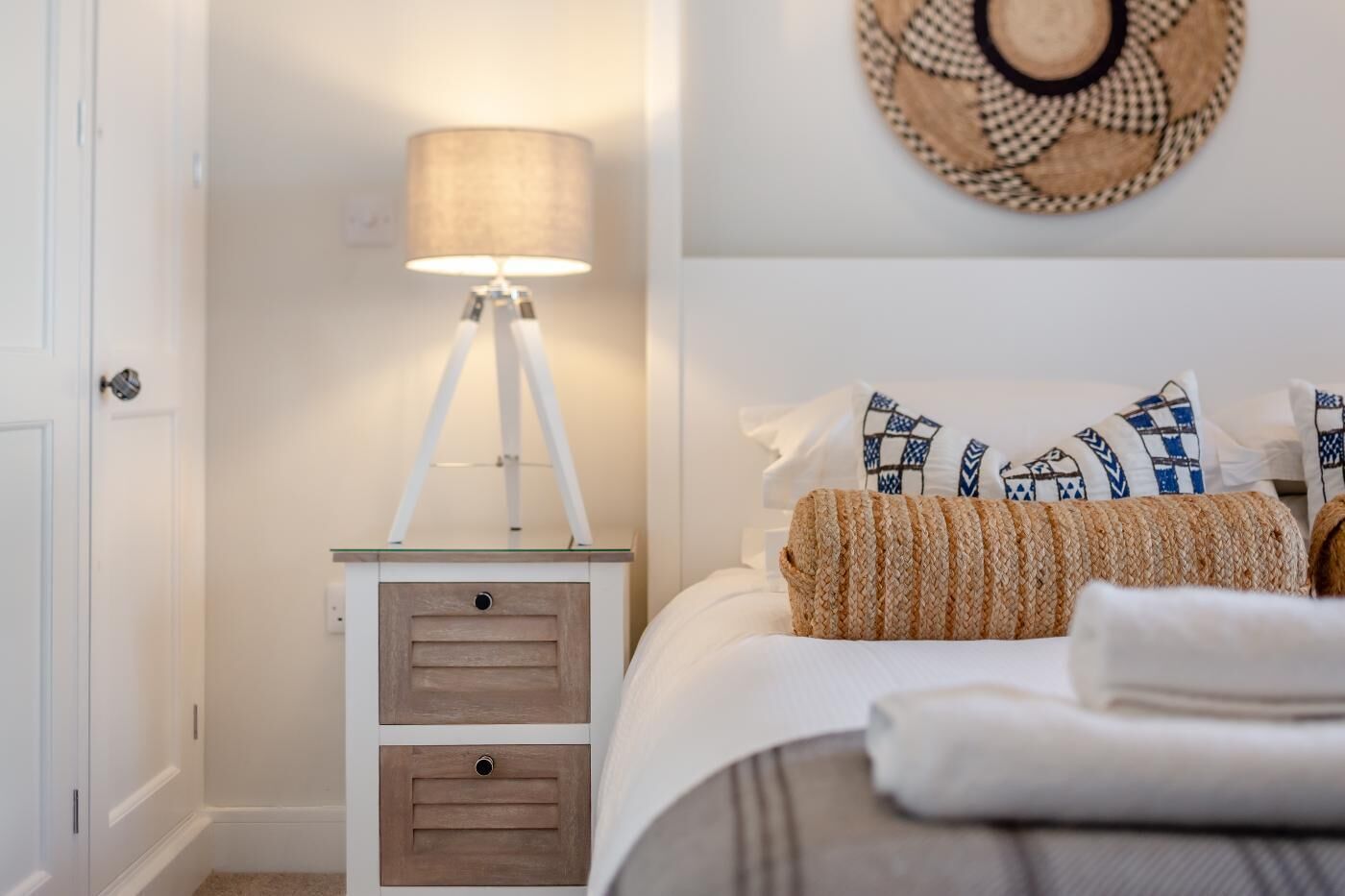 Une chambre à coucher avec un lit, une lampe de chevet, une décoration murale en tissu tissé et des coussins à motifs.