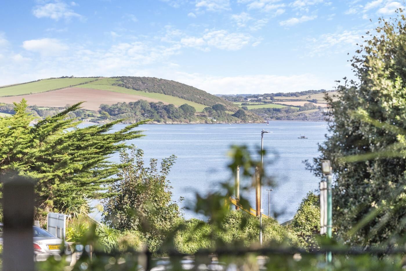 A view of a lake with hills in the background, surrounded by greenery.