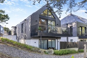 A modern two-story house with a balcony, large windows, and a sloped roof. - 2 Bed in Padstow (oc-t29016) (Padstow)