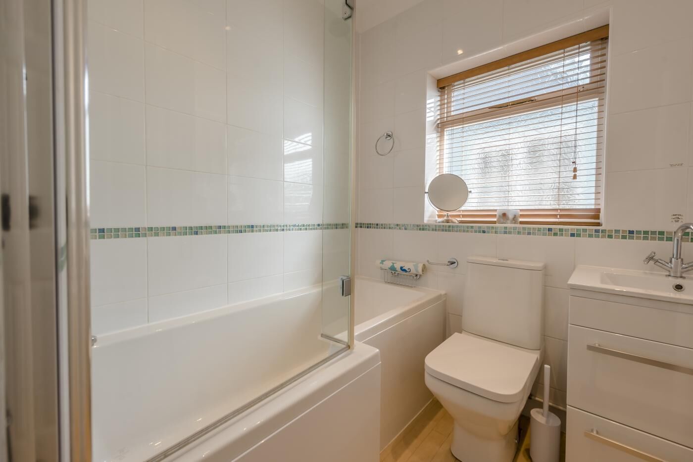 A bathroom with a glass-enclosed shower, a toilet, and a sink with a mirror above it.
