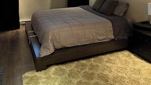 Un dormitorio con cama, ventana, un cuadro de una motocicleta y una lámpara en el techo.