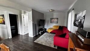 Una sala de estar moderna con un sofá rojo, un televisor de pantalla plana y una mesa de centro de madera.