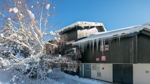Um edifício com telhado coberto de neve e escorpiças penduradas.